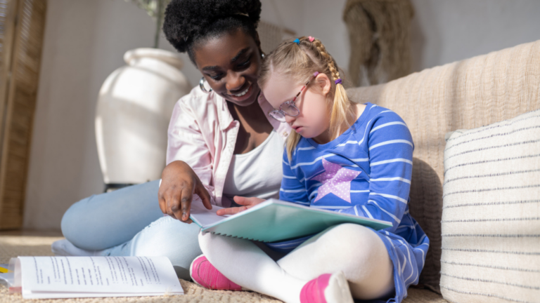 A girl with down syndrome reading something with her teacher